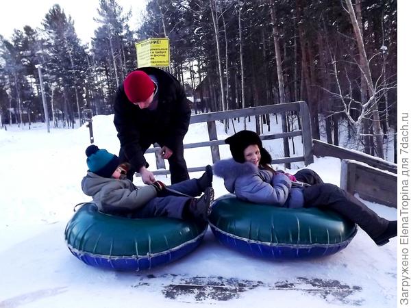 Лола и Дима готовятся съехать с горы на тюбах .
