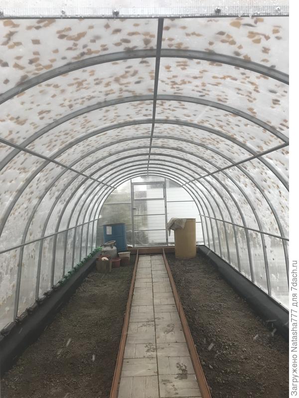 Теплица покрыта снегом и желтыми осенними листьями