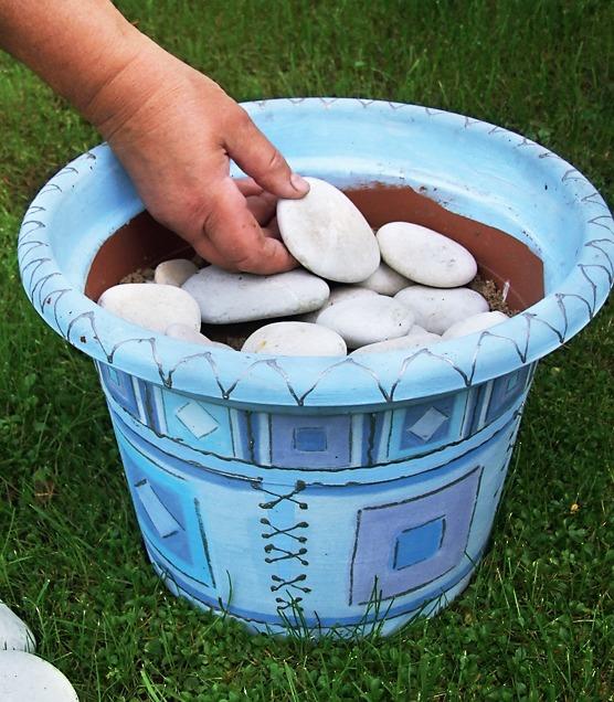 Красиво разложите гравий или крупную гальку поверх песка