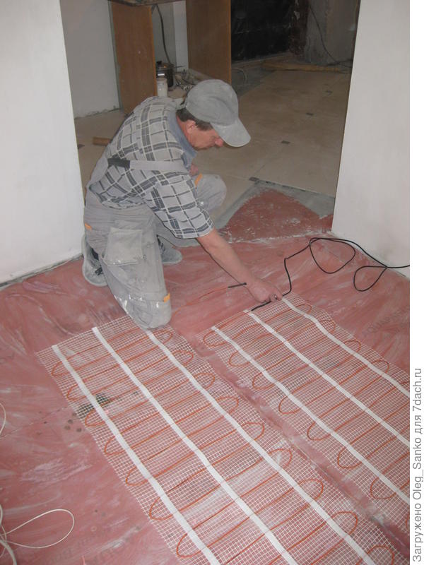 Универсальный мастер Александр монтирует  теплый пол.