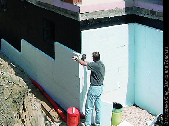 Фундамент уже гидроизолирован битумной мастикой, на фото запечатлен процесс теплоизоляции.