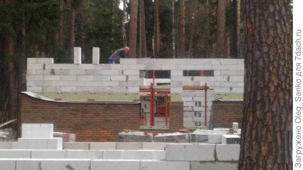 каменщик &quot;поднимает&quot; стену, одновременно кладя блоки, утеплитель и облицовочный кирпич