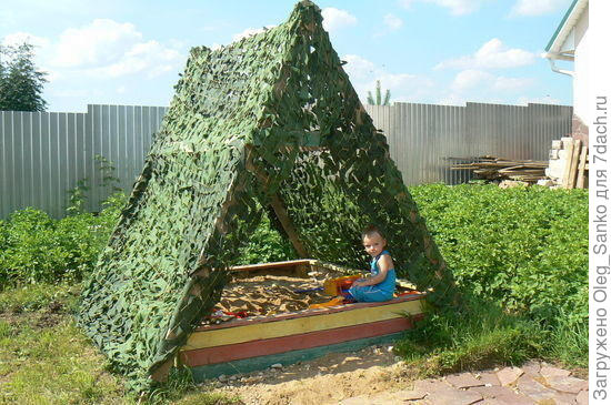 Маскировчная сетка  тут использована не по прямому назначению - она лишь тент, спасающая ребенка от лучей солнца.