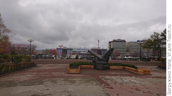 Памятник жертвам землетрясения в Нефтегорске. Вдали железнодорожный вокзал.