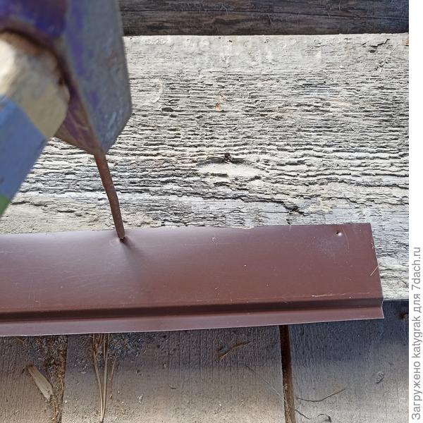 С помощью молотка и гвоздя пробивала отверстия в верхней части металлической полоски