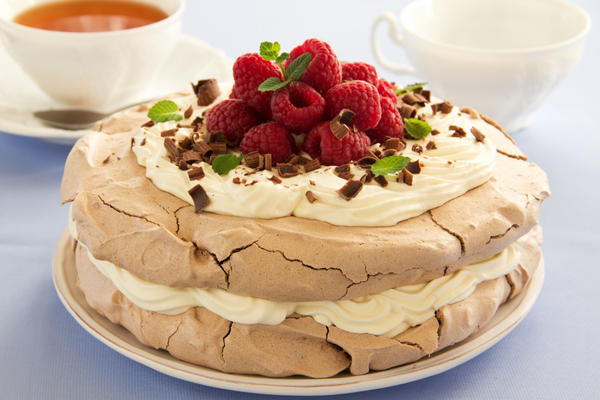 Торт «Павлова» из двух слоев меренги, украшенный малиной и шоколадной крошкой