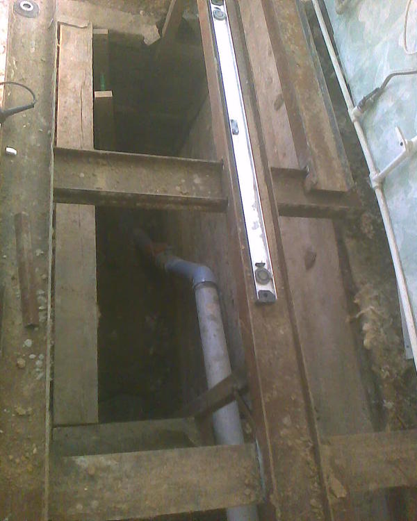 Ну там вот такое. Это - канализационная труба, она идет в септик. Здесь в неё будут входить два слива - с душевого бокса-ванны и от душевой кабинки (мы долго изобретали, потому что я люблю дрыхнуть в ванне, а ротели не любят лазить в ванны из-за их высоких бортов, ну и кончилось тем что порешили водрузить в помещении и то и другое, благо места хватило. Чуть дальше (ну или ближе если на фото смотреть) эта труба имеет ответвление для слива промыва бассейнового песчаного фильтра, там же входит туда слив стиральной машины (она у нас долго болталась по дому туда-сюда и кончилось тем что встала &amp;quot;в уголок&amp;quot; в помещении бассейна, ну и сама эта толстая труба - она идет с другой части дома, там унитаз, кухонная мойка, потом там еще сливы в другом месте с подсобной кухни... Вот. И если эта труба забивается - то в доме очень &amp;quot;весело&amp;quot; становится, нигде ничего нельзя сливать. Ну, она у нас за 15 лет эксплуатации торжественно забилась, и её пришлось откопать. А я потом подумал, ну чего я в случае разных приключений буду её каждый раз чет там ползать и откапывать? И решил оформить смотровую яму. Там оранжевое виднеется - это труба с отвинчивающейся панелькой, можно смотреть внутрь (что там делается), ну и дальше вот эти трубы. Был у меня б/у, но вполне приличный и сухой брус, остатки рубероида - ну и эту яму отделали наподобие погреба. А сверху уже конструкция из двутавров, какого-то швеллера и прочих железяк.