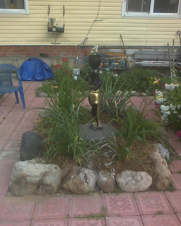 Получилось вот что-то такое. Правда лилейники после раздвигания недурно бы завтра как следует водой отлить, а то я поливал, но погода чересчур сухая, хоть бы дождик прошел... Статую ставил на круглый бетонный постамент, а потом обмазал периметр кругом густым бетоном вроде коровьей лепешки или как раньше канализационные люди торчащие обмазывали, чтобы она там наглухо стояла и на завалилась. Вроде вышло вполне культурно, правда цементом немного листья обрызгал когда заносил. Но я думаю ничего, они же постоянно растут. На зиму статую буду накрывать мешком из под зерна или еще чем-то таким.