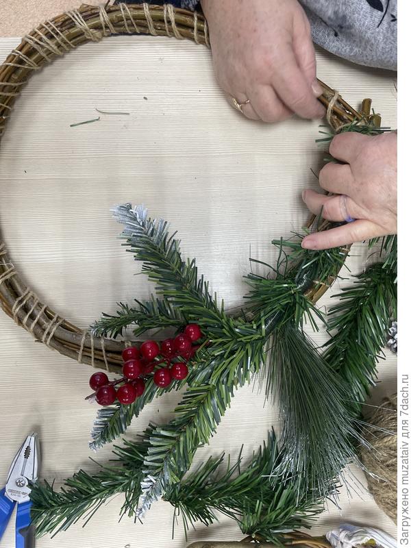 С помощью горячего пистолета на часть нашего основания прикрепляем искусственные ветки ели , ветки ягод, игрушки, шишки, орехи