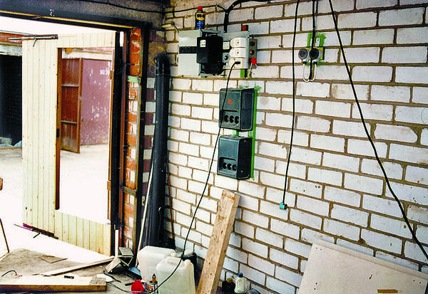 Рабочий момент монтажа электропроводки в гараже. Щит расположен у входа. Для освещения подвала на стене установлены трансформаторы 220/36 В