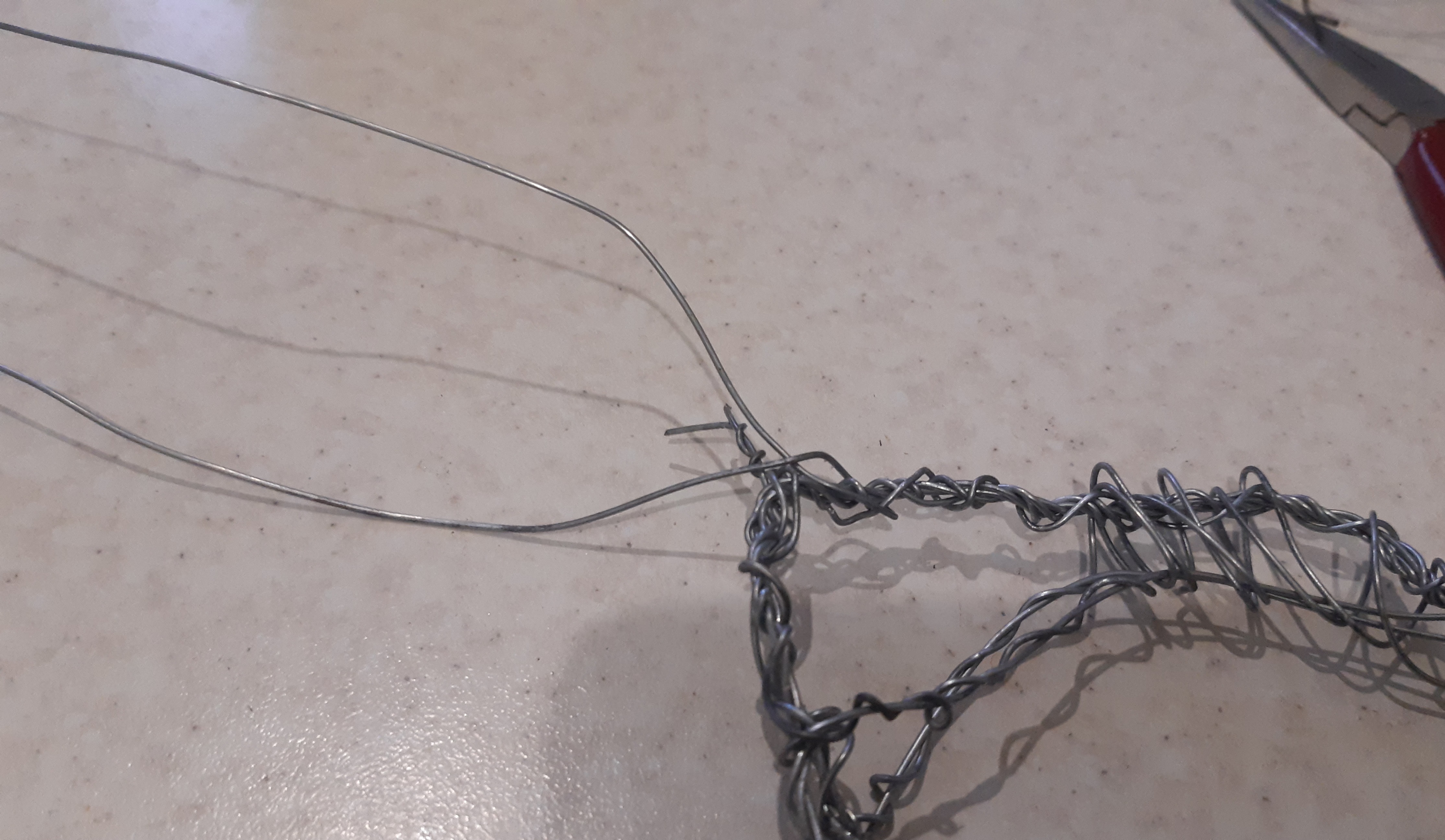 Длинную проволоку сгибаем пополам и пропускаем под той частью, где туловище переходит в шею